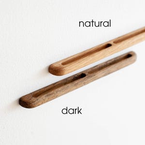 May include: Two wooden drawer pulls, one in a natural wood finish and the other in a dark wood finish. The pulls have a rectangular shape with a cutout in the center.