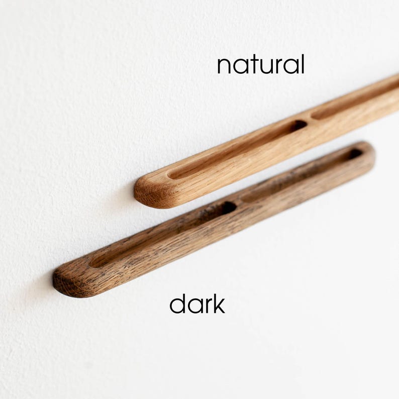 May include: Two wooden drawer pulls, one in a natural wood finish and the other in a dark wood finish. The pulls have a rectangular shape with a cutout in the center.