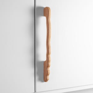 Könnte beinhalten: Ein Set aus drei Keramikbechern mit gesprenkelter, matter Oberfläche. Die Becher sind in Creme-, Hellgrau- und Dunkelgrautönen gehalten. Jeder Becher hat ein schlichtes, minimalistisches Design.