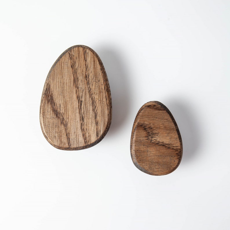 Pu&ograve; includere: Due ganci da parete in legno a forma di uovo. I ganci sono in legno marrone scuro con una venatura naturale.
