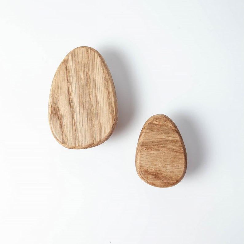 Pu&ograve; includere: Due ganci da parete in legno a forma di uovo. I ganci sono in legno marrone chiaro con una venatura naturale.