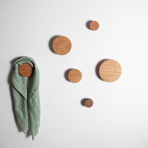 May include: Five wooden wall hooks in various sizes, with a green scarf hanging on one of the larger hooks.