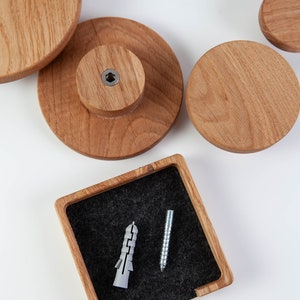 May include: Four wooden wall hooks in different sizes, with a small wooden box containing a screw and a plastic anchor. The hooks are made of natural wood and have a smooth finish.