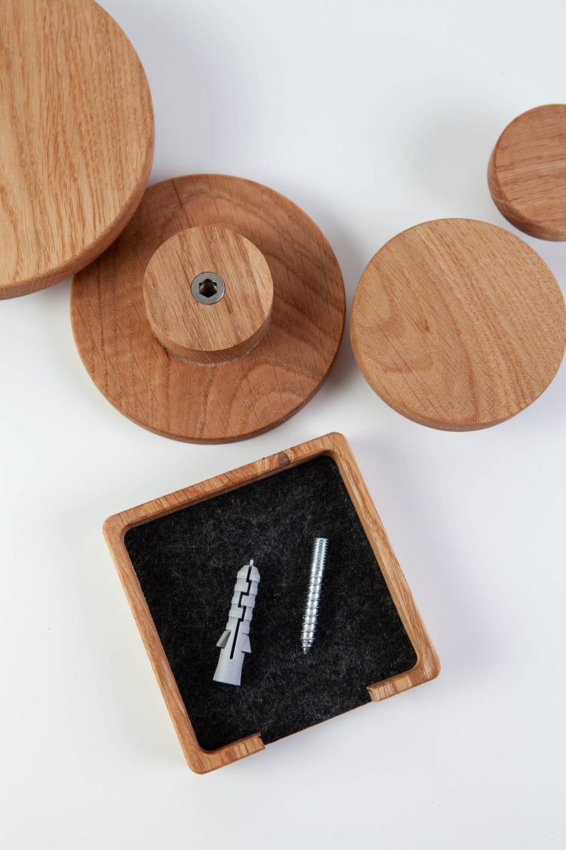 May include: Four wooden wall hooks in different sizes, with a small wooden box containing a screw and a plastic anchor. The hooks are made of natural wood and have a smooth finish.