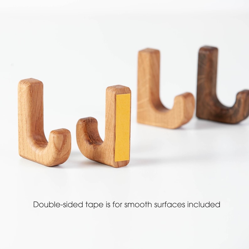 May include: Four wooden hooks with a J-shape design. The hooks are made of natural wood and have a light brown color. Double-sided tape is included for smooth surfaces.