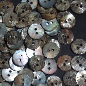 May include: A pile of brown and iridescent shell buttons with two holes each. The buttons are arranged in a random pattern and are all the same size.