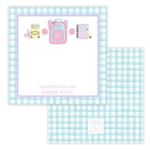 Peut inclure: Une carte à motif vichy bleu et blanc avec une bordure violette. La carte a un espace blanc pour écrire un message. Le haut de la carte représente un sac à dos rose, une boîte de crayons, une pomme rouge et un cahier violet avec un crayon. Le texte "Lunchbox Note for EMERY KATE" est imprimé sur la carte.