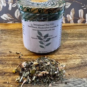 Puede incluir: Un frasco de vidrio lleno de té de hojas sueltas etiquetado como "Headache Rescue" con el texto "Intentional Teas LLC, Small Batch, Handcrafted Grayslake, IL, www.intentionalteasllc.com, Soporte natural para migrañas y dolores de cabeza, Peso neto 1 oz".