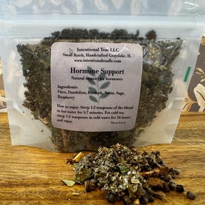 May include: A small resealable bag containing a blend of dried herbs for hormone support. The bag is labelled "Intentional Teas LLC" and lists the ingredients: Vitex, Dandelion, Burdock, Neem, Sage, and Raspberry. The label also includes instructions for steeping the tea.