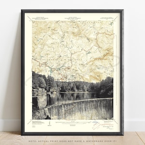 May include: Framed vintage topographic map print of the Nantahala National Forest and Fontana Lake in North Carolina. The map is in sepia tones with a black and white photograph of the dam and lake below. The frame is black.