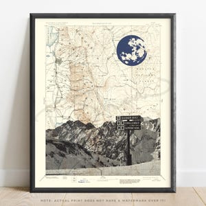 May include: Framed art print featuring a vintage map with a dark blue moon graphic. Below the map are mountain illustrations and a signpost with directional arrows. The signpost reads "Easier Way", "Challenger", and "Supreme Bowl".