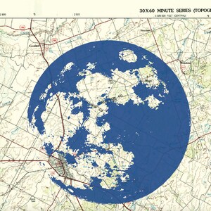 May include: A blue circle overlaying a topographic map. The circle is centered over a city with roads and rivers. The map shows the text "30X60 MINUTE SERIES (TOPOGRAPHIC)" and "3,025,000 FEET (CENTRAL)".