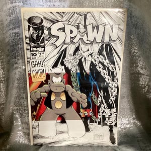 May include: A comic book titled "Spawn" featuring a black and white illustration of a character with chains and a skull, and a cartoon character. The cover includes the text "GAH! COLOR!"