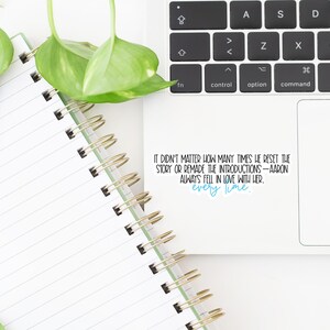 May include: A white spiral notebook with lined pages, a black pen with a floral design, and a laptop keyboard. The image includes a sticker with the text "IT DIDN'T MATTER HOW MANY TIMES HE RESET THE STORY OR REMADE THE INTRODUCTIONS - AARON ALWAYS FELL IN LOVE WITH HER. every time."