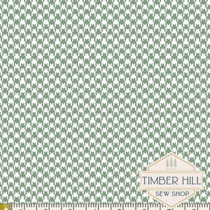 May include: Green and white houndstooth pattern fabric with a measuring tape along the bottom. The fabric has a repeating pattern of small, stylized dog tooth shapes. The Timber Hill Sew Shop logo is in the bottom right corner.