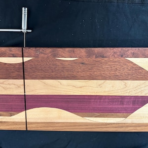 Tabla de quesos de madera variada con diseño ondulado.