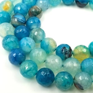 Può includere: Una collana di perle di agata sfaccettate in tonalità di blu e verde. Le perle hanno una forma unica e irregolare e un aspetto traslucido.