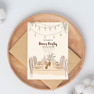 Puede incluir: Una tarjeta de invitación beige con texto marrón que dice "You're Invited To A Dinner Party Saturday, May 15th 6:30 pm at The Smith's House 1234 Wonder It Down, NY RSVP To Samantha". La tarjeta presenta una ilustración dibujada a mano de una mesa puesta con velas, platos y vasos.