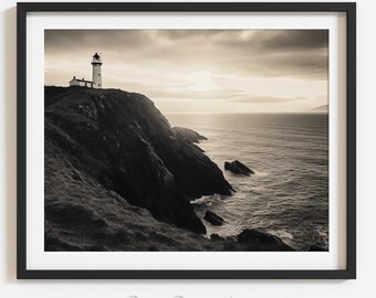 May include: A black and white photograph of a lighthouse on a cliff overlooking the ocean. The lighthouse is tall and white with a black roof. The ocean is calm and the sky is cloudy.
