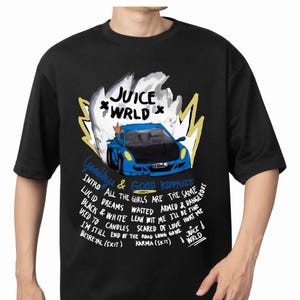 May include: Black t-shirt featuring a blue sports car graphic with the text "JUICE WRLD" and song titles. The design includes a stylized flame and handwritten text. The shirt is a crew neck.