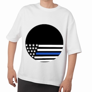 Może przedstawiać: Biała koszulka z czarnym okrągłym wzorem przedstawiającym stylizowaną flagę amerykańską. Projekt zawiera białe gwiazdy, białe i czarne paski oraz niebieską linię. Koszulka jest w stylu casual z krótkim rękawem.