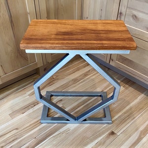 May include: A wooden top table with a silver metal base. The base is a geometric design with a diamond shape.