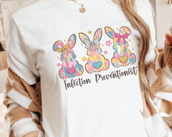 May include: White t-shirt with a graphic of three colorful bunnies with bows and the text "Infection Preventionist".