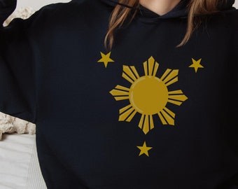 May include: Black hooded sweatshirt with a yellow sun and three stars graphic. The sun has eight rays and is surrounded by a circle of smaller rays. The stars are in the corners of the graphic.