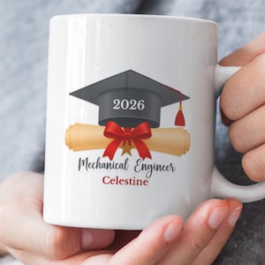 Könnte beinhalten: Weiße Keramik-Tasse mit Abschlusskappe, Diplom und rotem Schleifendesign. Die Tasse trägt den Text "2026 Mechanical Engineer Celestine". Ein Geschenk für einen Maschinenbau-Absolventen.