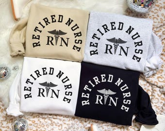 May include: Four sweatshirts in beige, gray, white, and black, each with the text "Retired Nurse" in a semi-circle above the RN symbol. The RN symbol is a caduceus. The words "Items sold separately" are at the bottom.