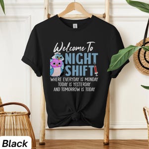 May include: Black t-shirt with a graphic of two owls wearing nurse hats and the text "Welcome to Night Shift" with the tagline "Where everyday is Monday, today is yesterday and tomorrow is today".
