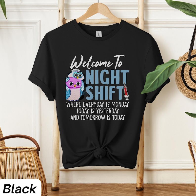 May include: Black t-shirt with a graphic of two owls wearing nurse hats and the text "Welcome to Night Shift" with the tagline "Where everyday is Monday, today is yesterday and tomorrow is today".