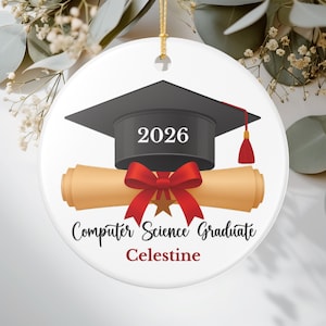 Puede incluir: Adorno de graduación de cerámica blanca con birrete negro, pergamino y lazo rojo. El adorno dice "2026", "Computer Science Graduate" y "Celestine". Una cuerda dorada está unida para colgarlo.