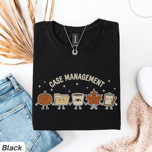 Może przedstawiać: Czarny t-shirt z napisem CASE MANAGEMENT wygiętym w łuk nad grafiką przedstawiającą pięć trzymających się za ręce postaci z kreskówek: dynię, segregator, kubek kawy, liść klonu oraz podkładkę z klipsem i ołówkiem.