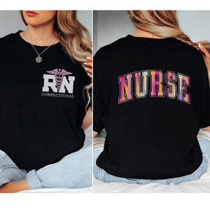 May include: Black t-shirt with a pink and purple "RN Correctional" graphic on the front and a rainbow "NURSE" graphic on the back.