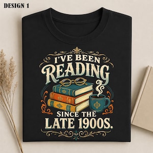 May include: A black t-shirt featuring a graphic of three stacked books, a pair of gold-rimmed glasses, and a steaming mug. The text reads, "I'VE BEEN READING SINCE THE LATE 1900S." The design includes ornate gold and orange decorative flourishes.