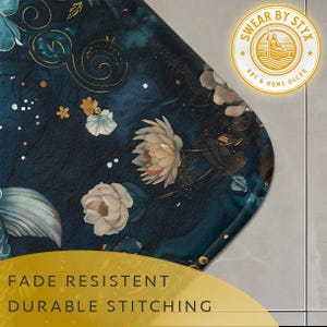 May include: A dark blue bath mat with a floral pattern featuring white and gold flowers. The mat has a rounded edge and the text "SWEAR BY STYX ART & HOME DECOR" is printed in a yellow circle in the top right corner. The text "FADE RESISTANT DURABLE STITCHING" is printed in yellow at the bottom of the image.