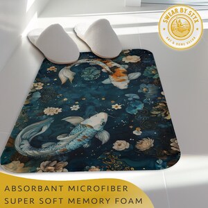 May include: A blue bath mat with a floral and koi fish design. The mat has a "Swear By Styx Art & Home Decor" logo in the top right corner. The text "Absorbant Microfiber Super Soft Memory Foam" is at the bottom of the image.