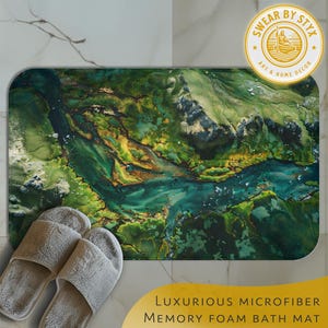 May include: A rectangular bath mat with a vibrant, abstract design resembling a landscape with green, gold, and blue hues. The mat is labeled "Luxurious Microfiber Memory Foam Bath Mat" and has a logo that says "Swear by Styx Art & Home Decor". A pair of gray slippers are in the foreground.