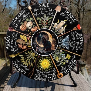 Pode incluir: Uma roda de madeira preta com oito se&ccedil;&otilde;es, cada uma representando uma &eacute;poca diferente do ano no calend&aacute;rio Wiccan. A roda &eacute; decorada com ilustra&ccedil;&otilde;es de plantas, animais e s&iacute;mbolos associados a cada esta&ccedil;&atilde;o. O texto na roda inclui os nomes das esta&ccedil;&otilde;es, as datas dos solst&iacute;cios e equin&oacute;cios, e os nomes das divindades associadas a cada esta&ccedil;&atilde;o.