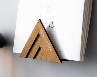 May include: A wooden record stand with the text "Now Playing" on it, holding a white vinyl record with the handwritten text "Pink Floyd The Wall". A black lamp with a round shade is in the background, and a turntable with a black vinyl record is in the foreground.