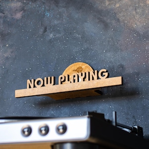 May include: A wooden wall mount with the words "NOW PLAYING" and a small wooden circle with the words "Vinyl Soul" on it. The mount is designed to hold a vinyl record.