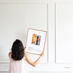 May include: A framed watercolor illustration of a vodka Red Bull cocktail. The illustration shows a glass with ice and a can of Red Bull. The text "Vodka Red Bull" is printed below the illustration.