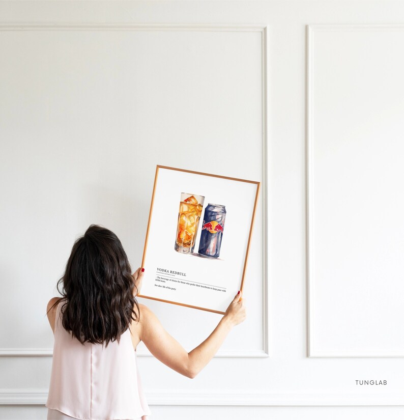 May include: A framed watercolor illustration of a vodka Red Bull cocktail. The illustration shows a glass with ice and a can of Red Bull. The text "Vodka Red Bull" is printed below the illustration.