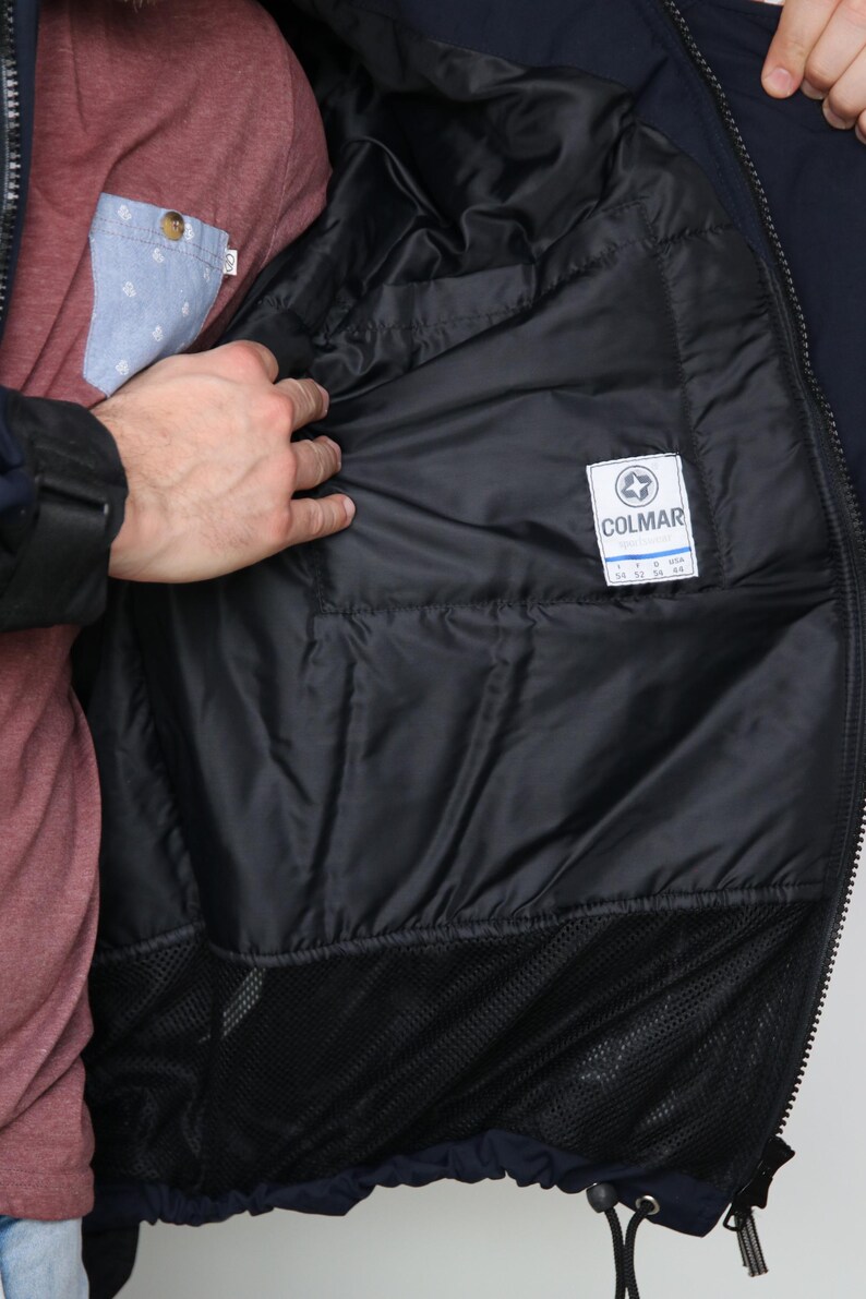 May include: A navy blue jacket with a black mesh lining and a white label that says "COLMAR" with size information.