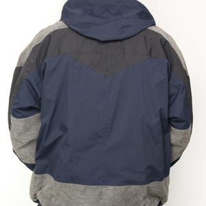 May include: A navy blue, black, and gray hooded jacket with a color-blocked design. The jacket has a zipper closure and a drawstring hood.