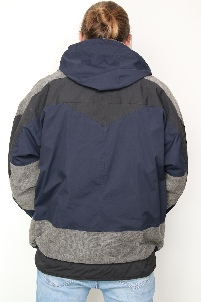 May include: A navy blue, black, and gray hooded jacket with a color-blocked design. The jacket has a zipper closure and a drawstring hood.