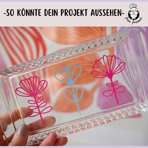 May include: A clear glass rectangular tray with a textured surface. Three stylized flower designs are adhered to the tray. One flower is blue, and two flowers are pink.
