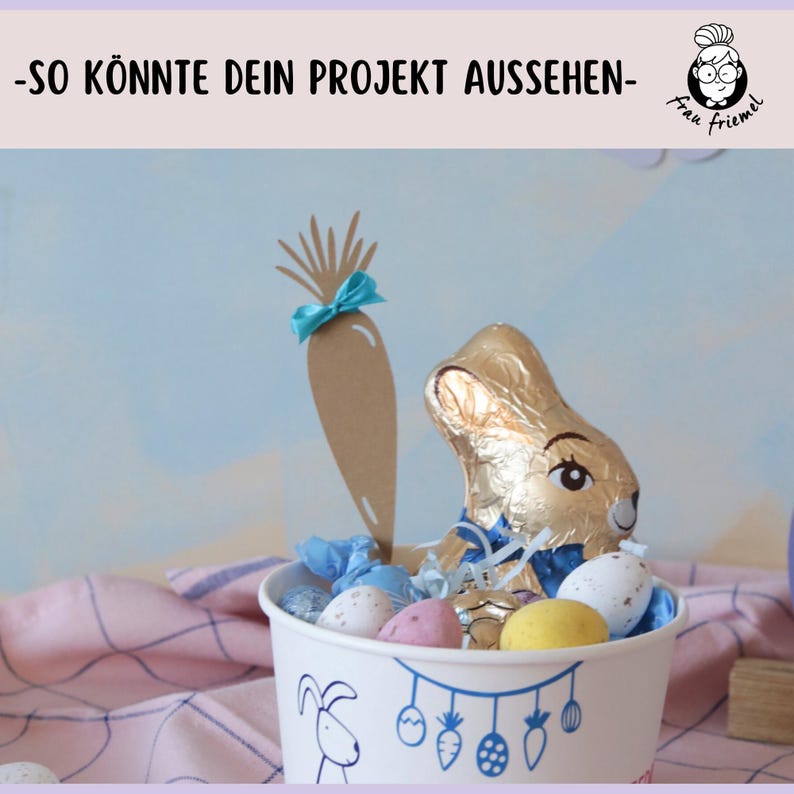 Puede incluir: Una cesta de Pascua de cer&aacute;mica blanca con un conejo azul y zanahorias, huevos y bayas colgantes. La cesta est&aacute; llena de huevos de chocolate, un conejo de chocolate y papel de seda azul y blanco.