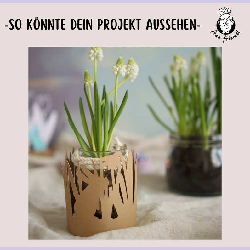 Pu&ograve; includere: Due vasi di vetro con fiori bianchi sono decorati con ritagli di carta marrone. I ritagli hanno la forma di erba e fiori. I vasi sono su una superficie bianca.